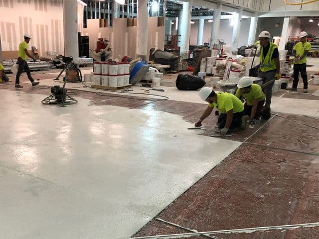 Équipe au travail sur un sol terrazzo dans un espace commercial en construction