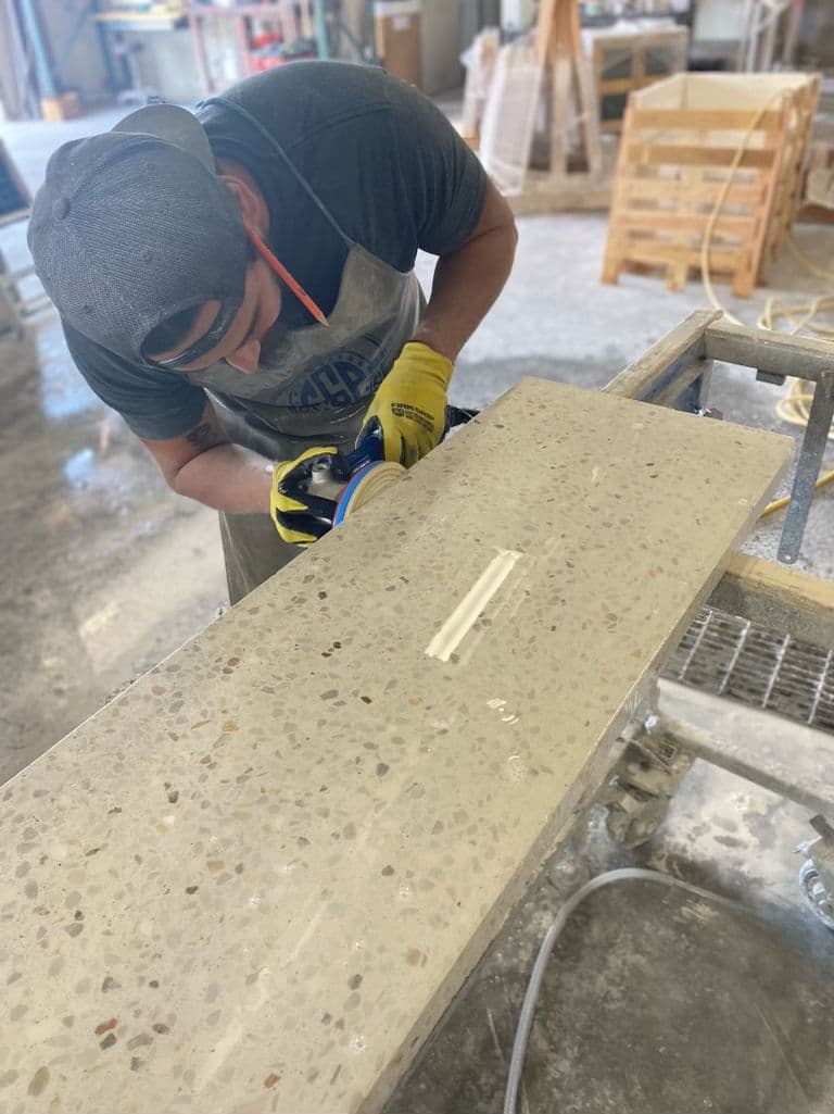 Artisan concentré sur le ponçage d'un plan en terrazzo