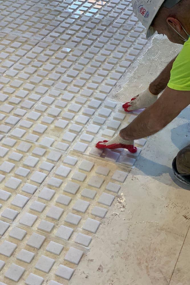 Pose de petits carreaux de marbre, technique proche du terrazzo en pièce d'eau